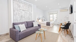 Una sala moderna con un sofá gris, una mesa de centro de vidrio y un comedor con una mesa y sillas.