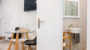 Un baño moderno con cabina de ducha de vidrio, un lavabo con toallero y una pequeña mesa con sillas.