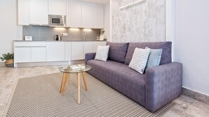 Una sala moderna con un sofá gris, una mesa de centro de vidrio y una alfombra estampada.
