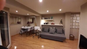 Una sala moderna con un sofá gris, una mesa de comedor con sillas y una pequeña mesa de centro.