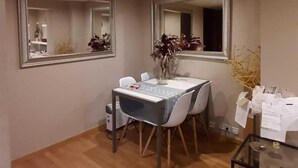 Un comedor con piso de madera, una mesa con sillas y dos espejos colgantes.