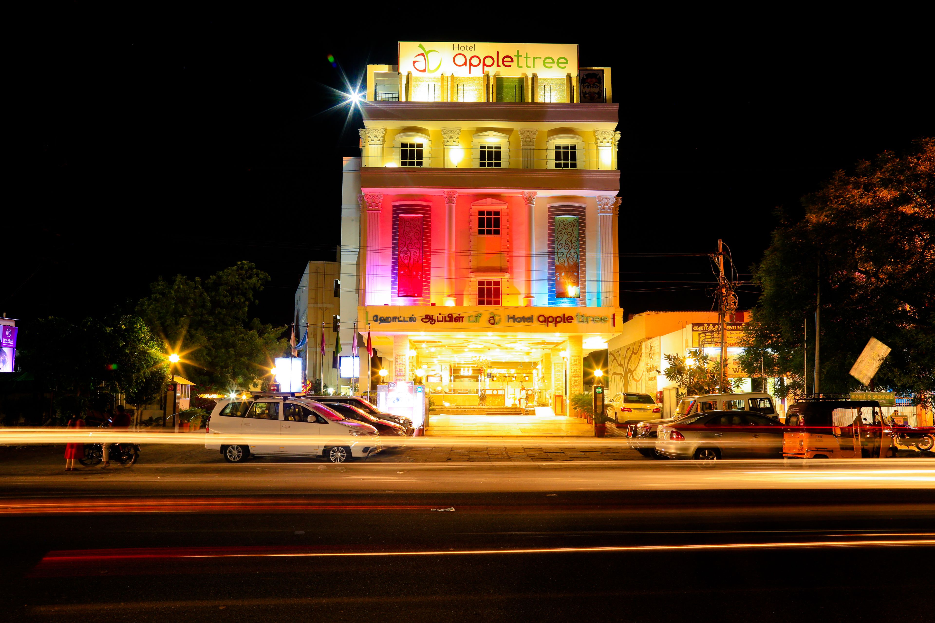A multi-story hotel with a brightly lit facade and signage reading "Hotel Applettree."