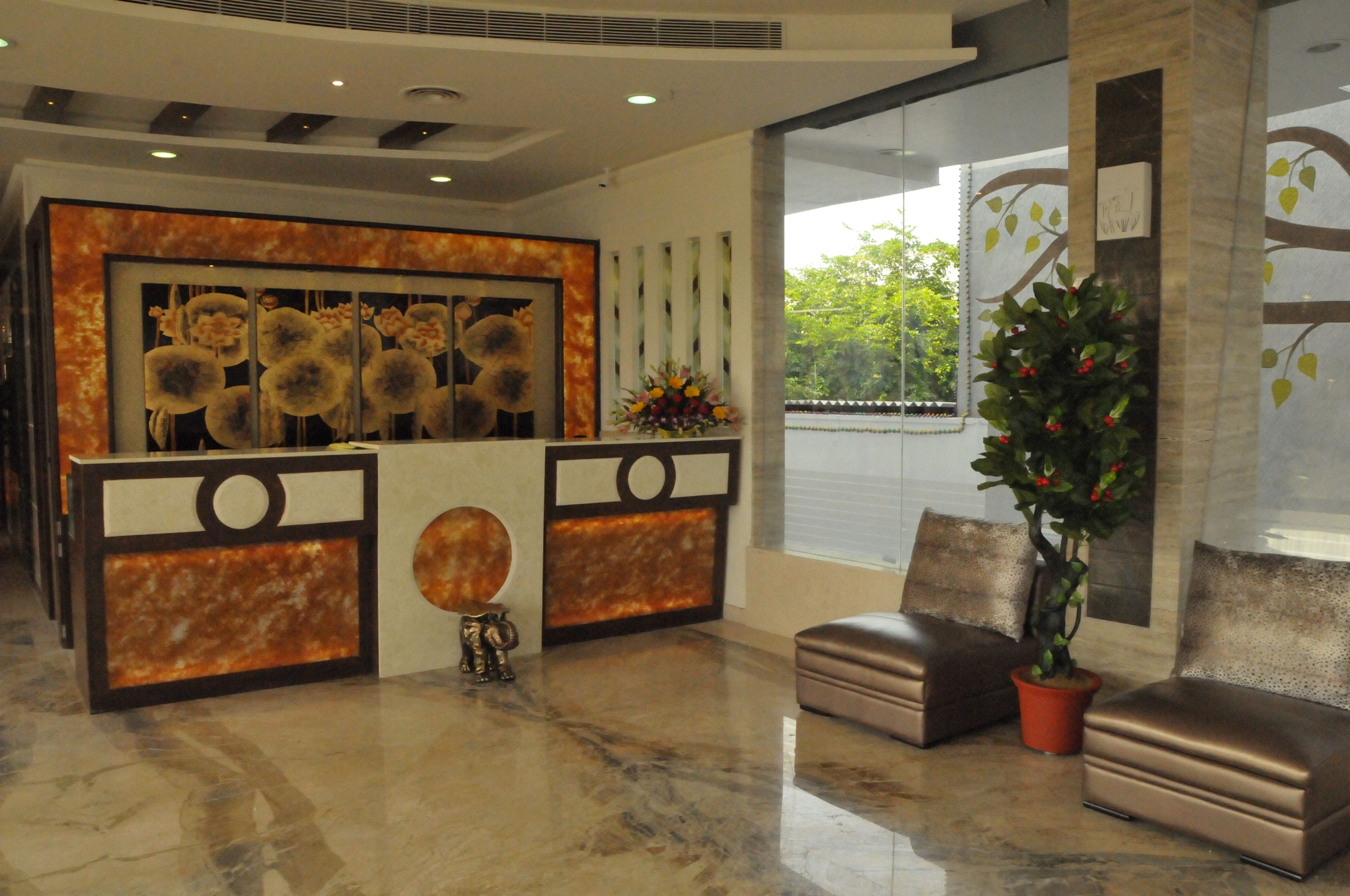 A reception area with a marble floor, two leather sofas, a potted plant, and a decorative wall with abstract art.