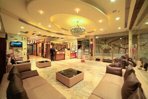Un'ampia hall con reception, divani, tavolino da caffè e lampadario.