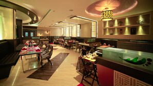 Un restaurante moderno con una larga mesa común dispuesta para comer, mesas individuales y un mostrador con una escultura decorativa de un pez.