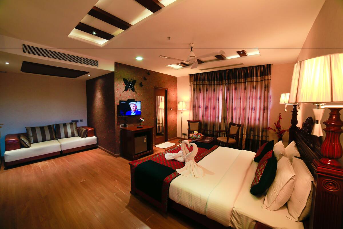 A hotel room with a bed, a sofa, a TV, and a desk.