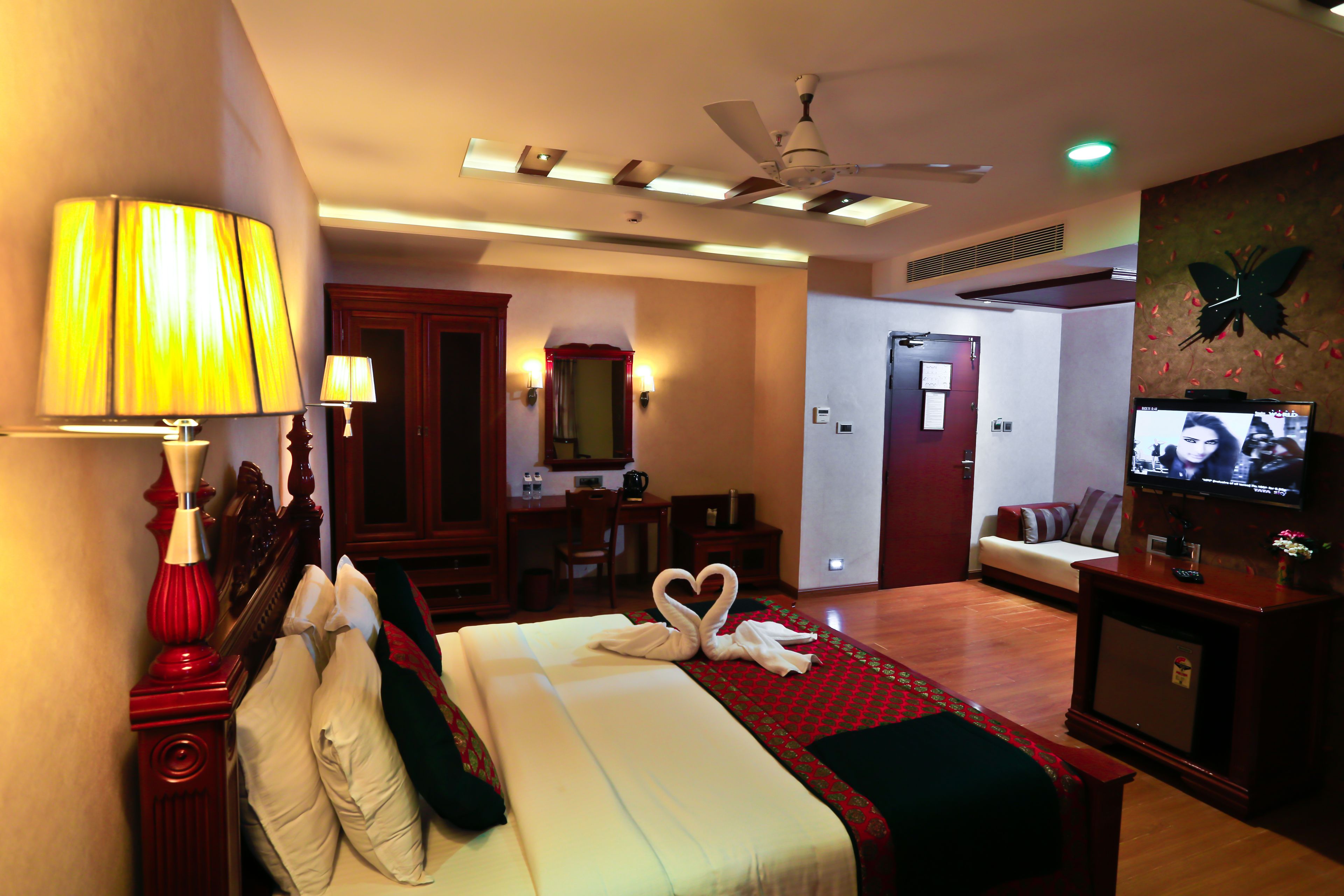 A hotel room with a bed, a desk, a television, and a ceiling fan.