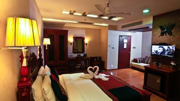 A hotel room with a bed, a desk, a television, and a ceiling fan.