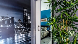 A room with a bed, a blue wall, and a large bamboo plant. - Apt in Puerto Rico 100m From the Beach, Free Wifi, Community Pool and Garden (Las Palmas)
