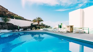 A swimming pool with lounge chairs and a stone wall. - Apt in Puerto Rico 100m From the Beach, Free Wifi, Community Pool and Garden (Las Palmas)