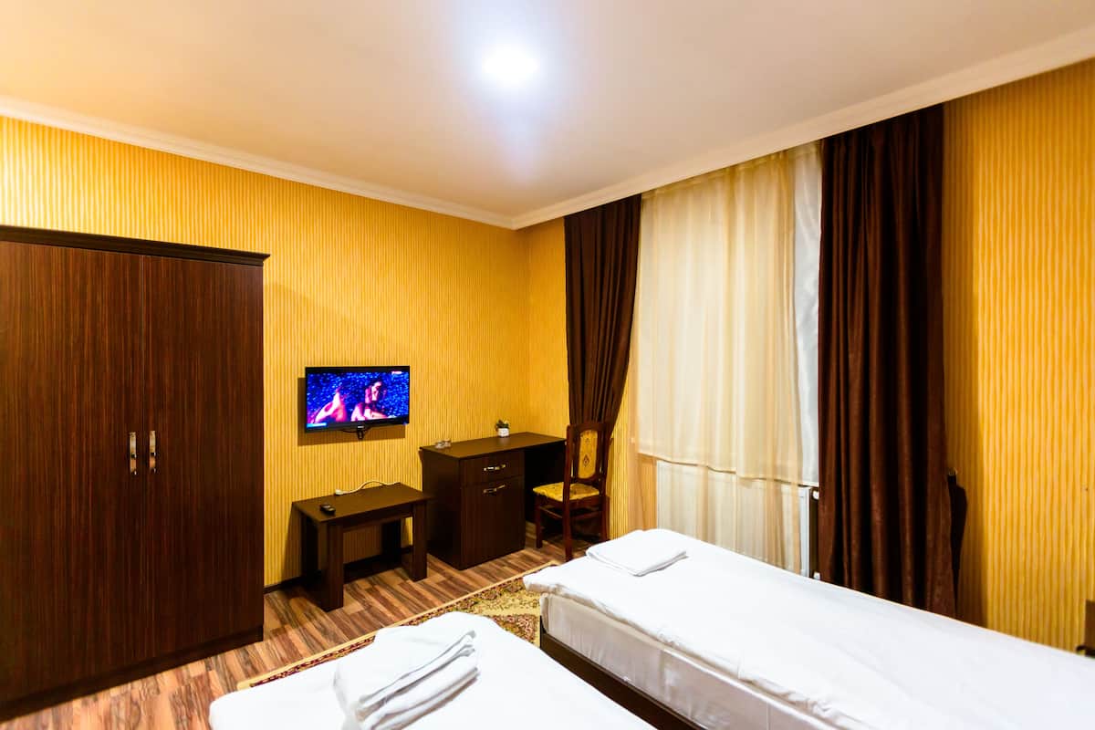 Une chambre d’hôtel avec deux lits, un bureau, une télévision et une armoire.