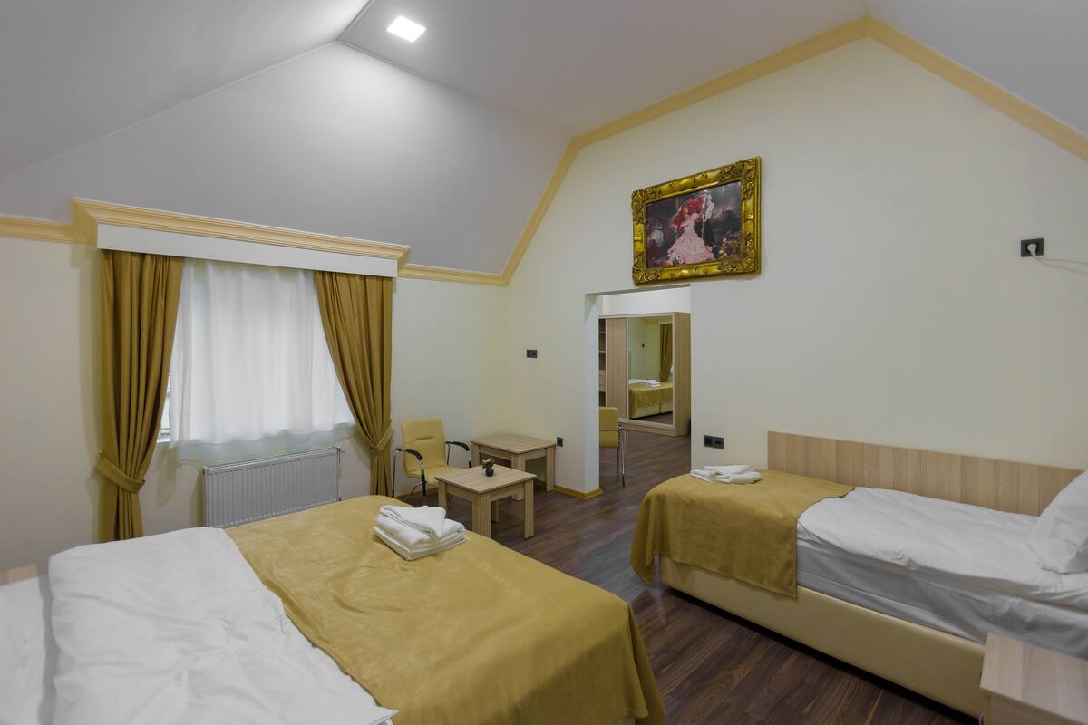 Une chambre d’hôtel avec deux lits, une petite table, une chaise, un miroir et un tableau au mur.