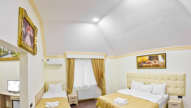 A hotel room with two beds, a desk, a computer, and a window with curtains. - Renessans Hotel Baku (Baku)