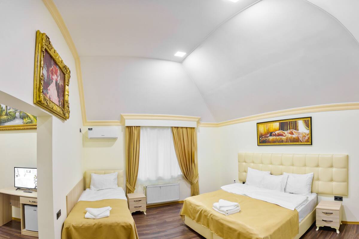 Une chambre d’hôtel avec deux lits, un bureau, un ordinateur et une fenêtre avec des rideaux.
