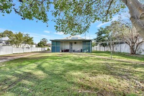 A residential property with a house, fenced yard, and a tree.