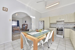 A compact kitchen with a dining table, chairs, and a built-in oven. - Discover Cessnock Vineyard Delights - Book Direct (Cessnock)