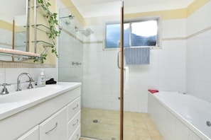 A bathroom with a shower, a sink with a mirror, and a window. - Discover Cessnock Vineyard Delights - Book Direct (Cessnock)