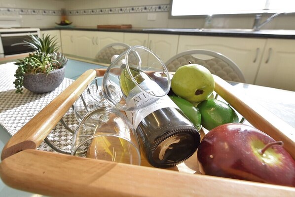A tray with a bottle, glasses, and fruits on a table in a kitchen. - Discover Cessnock Vineyard Delights - Book Direct (Cessnock)
