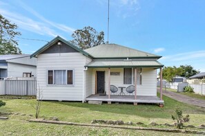 A single-story house with a porch, two chairs, and a small table. - Discover Cessnock Vineyard Delights - Book Direct (Cessnock)