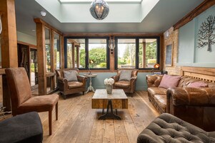 Una habitación con mobiliario de cuero, una mesa de centro de madera y ventanas grandes con vistas a zonas verdes.