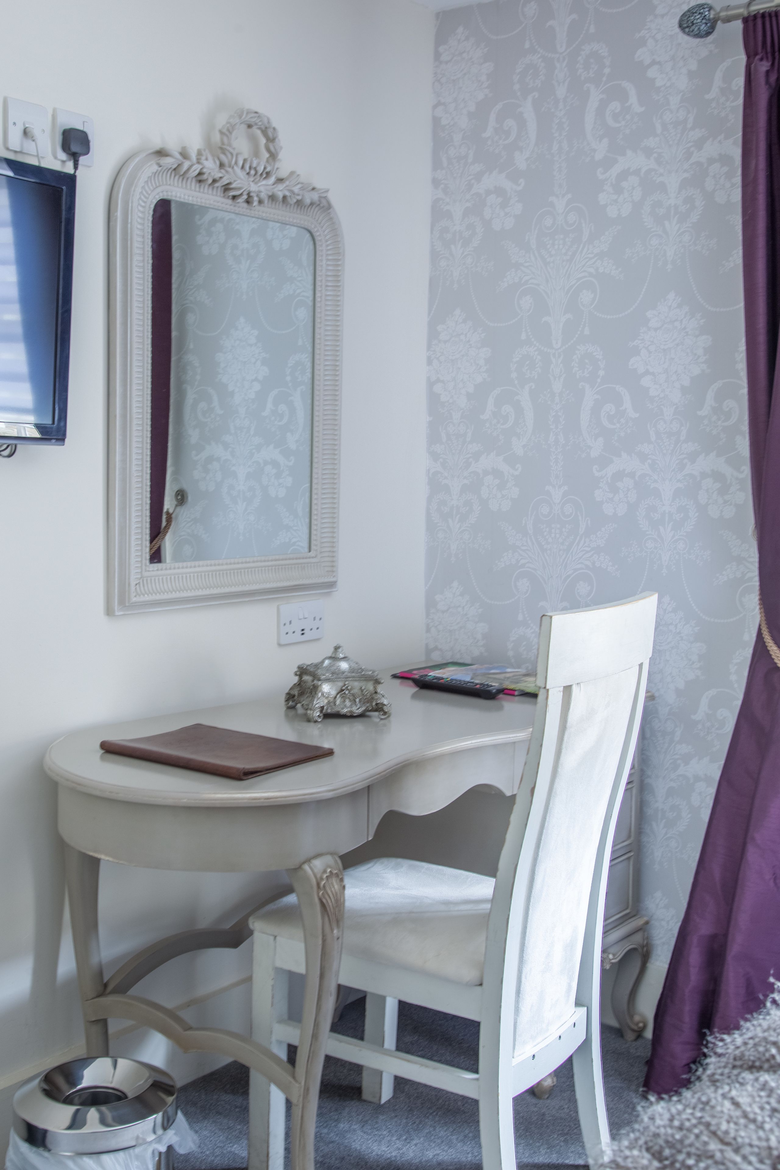 Une salle de bain équipée d’un meuble-lavabo, d’un miroir, d’une chaise et d’un rideau de douche.
