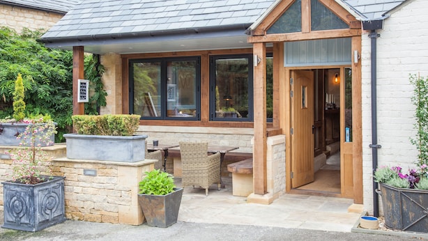 A building with a covered patio area, stone walls, and wooden doors.