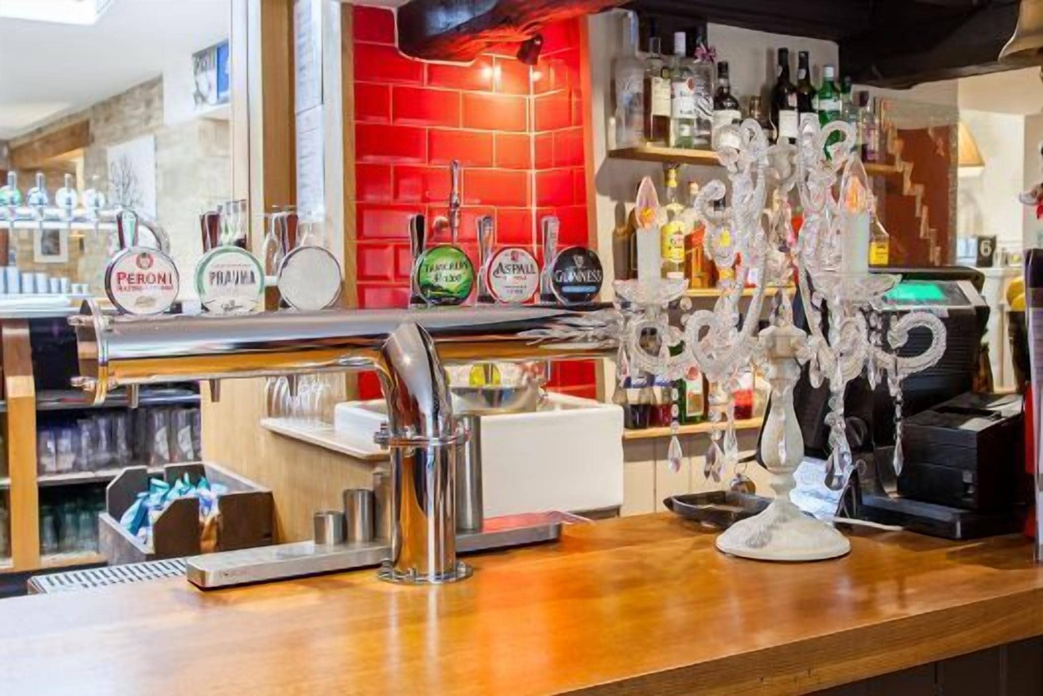 A bar area with a red tiled wall, a variety of liquor bottles, and a decorative ice sculpture.