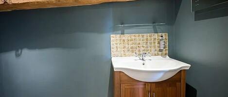 A bathroom with a wooden cabinet, a white sink, and a tiled backsplash.