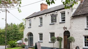 A traditional white building with a signboard, arched windows, and a door.