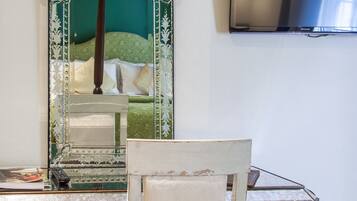 Una habitación con cama, espejo, televisor y una silla.