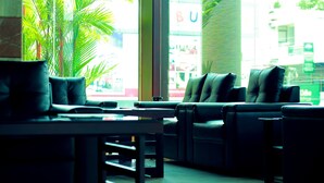 Un espace détente avec des fauteuils en cuir et une table, une plante en pot, et une vue sur un bâtiment dont on peut apercevoir l’inscription « BU » à travers la fenêtre.