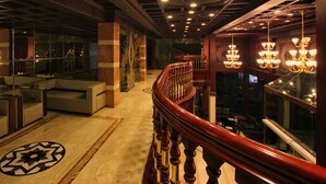 Un magnifique escalier avec une rampe en bois menant à un balcon doté d’une balustrade en verre.