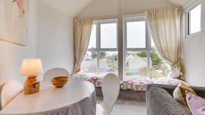 Une pièce chaleureuse avec une table ronde, une chaise, un lit avec une literie à motifs et une fenêtre avec des rideaux.