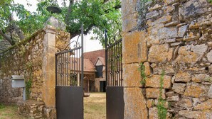 A rustic stone gate leading to a building with a tiled roof.