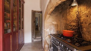 A kitchen with a stone wall, a stove, and a hanging light fixture.
