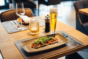 A dining table with a plate of food, a glass of beer, and a glass of water.