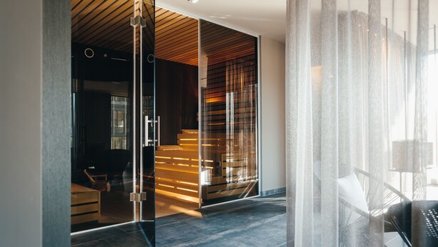 A modern interior with a glass partition, wooden slats, and a black chair. - VILOTEL - Hotel & Restaurant (Oberkochen)