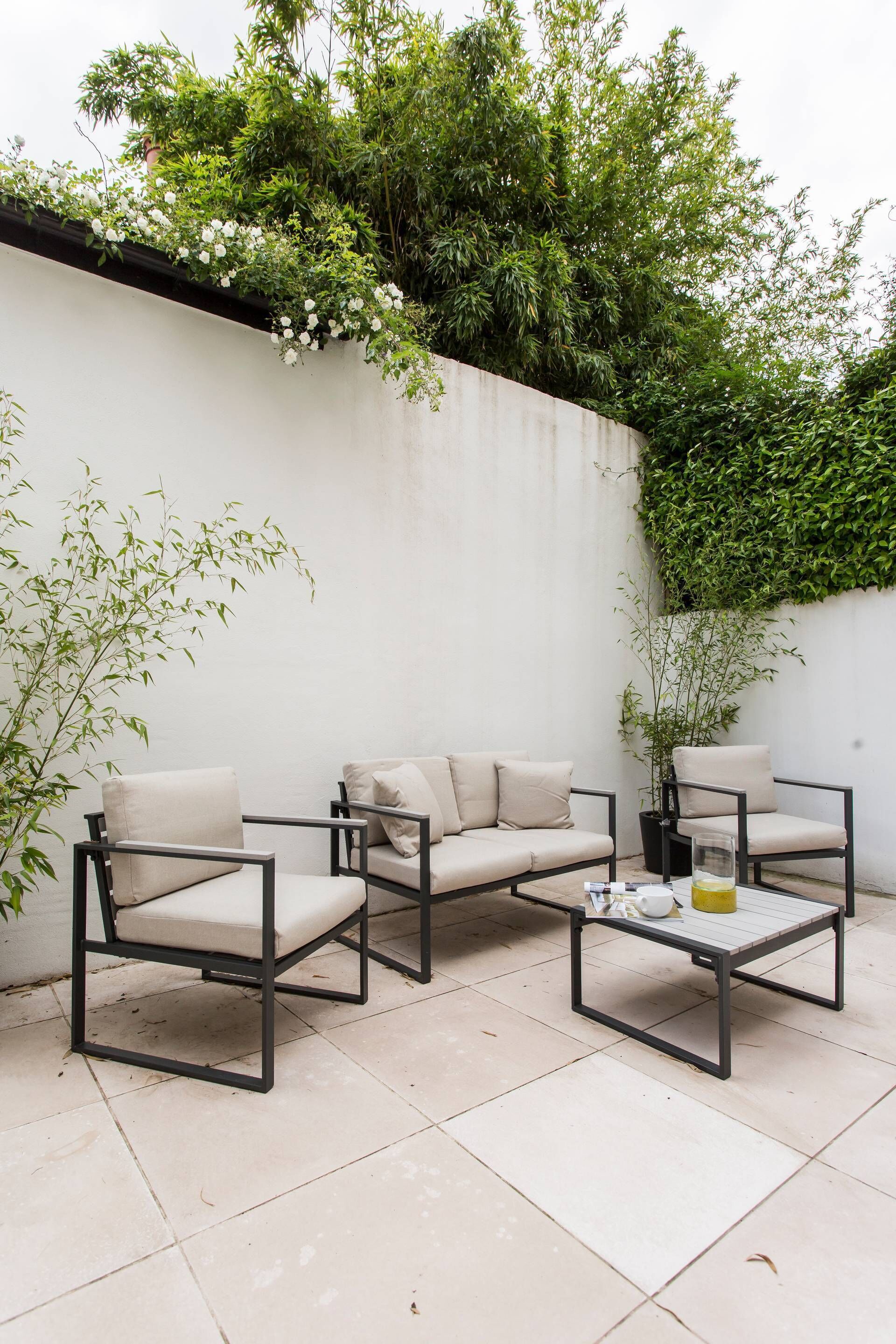 Een terras met een bank, twee fauteuils en een bijzettafeltje.