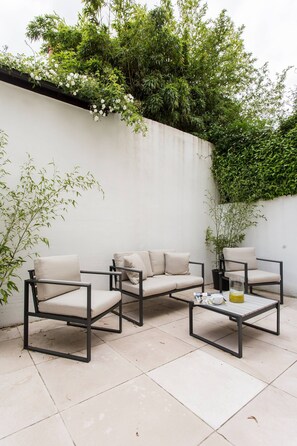 An outdoor seating area with a sofa, two armchairs, and a coffee table.