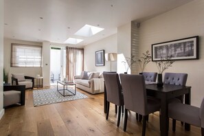 A modern living room with a dining area, featuring a sofa, chairs, a coffee table, and a dining table.