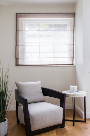 Une pièce avec une fenêtre, une chaise, une petite table et une plante en pot.