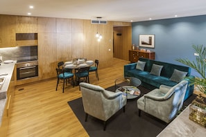 A modern living room with a dining area, wooden flooring, and a blue accent wall. - Abbey Apartments City Center I Bolhão Market (Porto)
