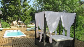 A wooden deck with a hot tub and a canopy bed. - Le Moulin Calme (Luceau)