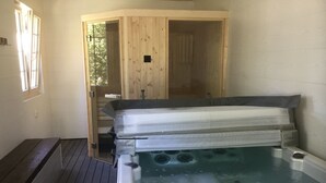 A hot tub in a room with wooden walls and a wooden deck. - Le Moulin Calme (Luceau)