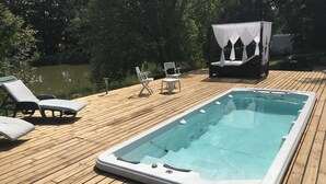 A wooden deck with a hot tub, lounge chairs, and a canopy. - Le Moulin Calme (Luceau)