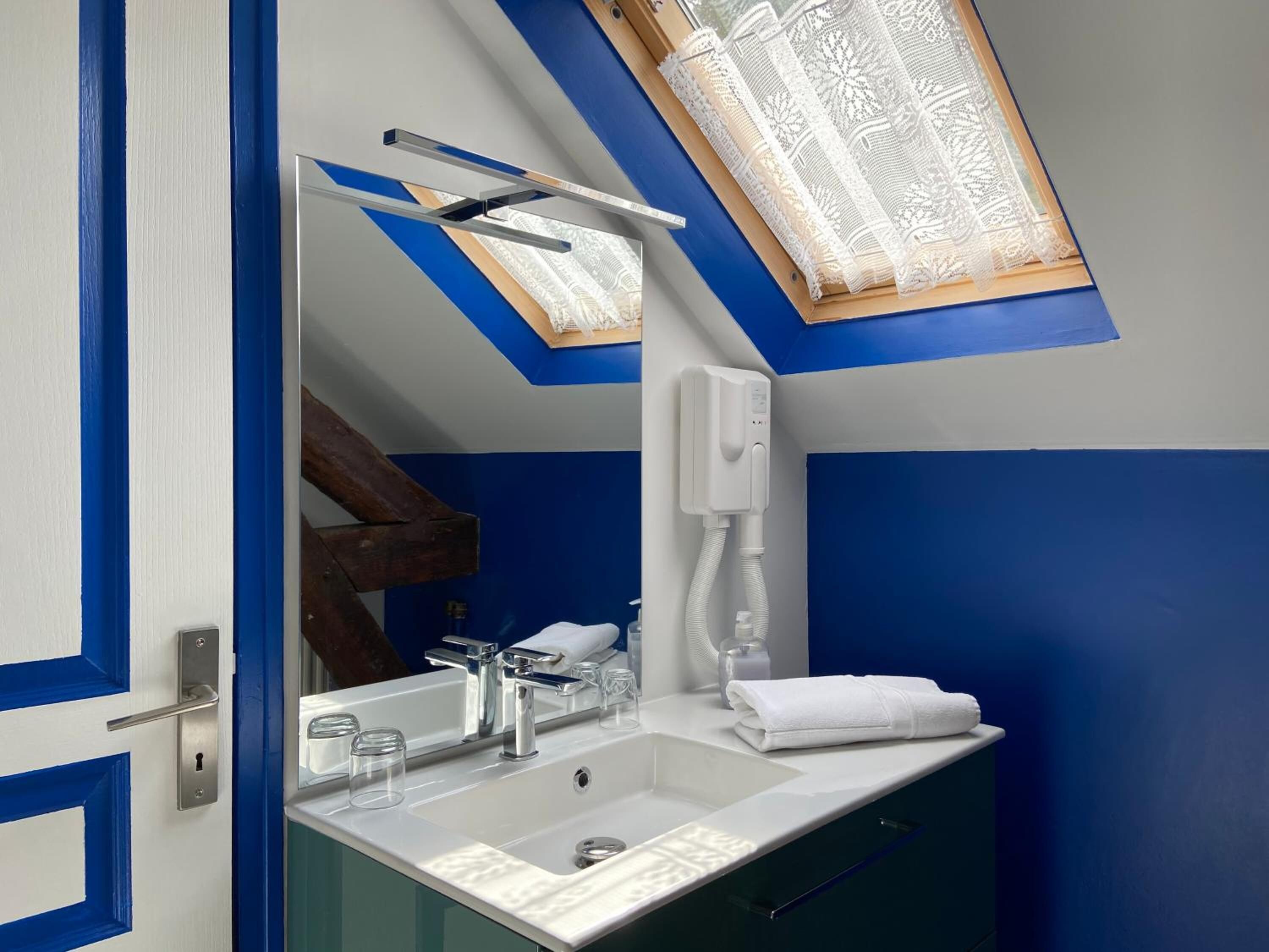 A modern bathroom with a skylight, a white sink, a mirror, and a towel on the counter.