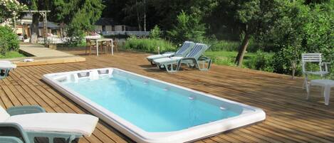 An outdoor swimming pool with lounge chairs and a wooden deck.