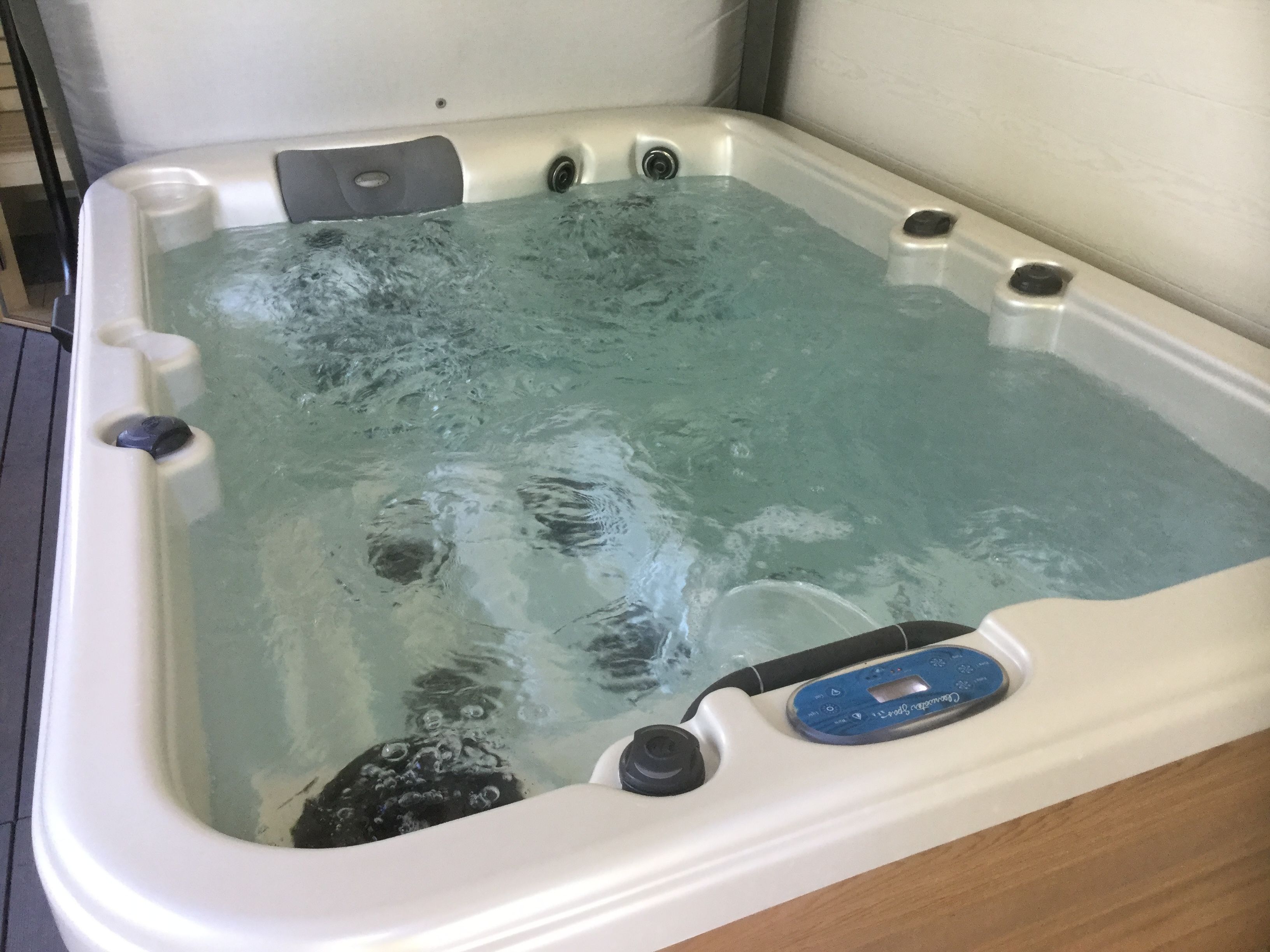 Un jacuzzi con panel de control, múltiples chorros y desagüe visible.