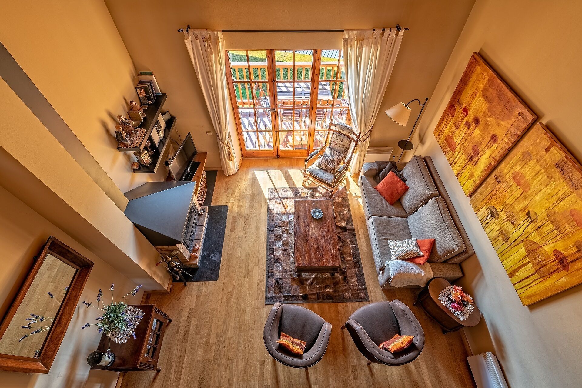 Un salon spacieux avec une grande fenêtre, un canapé, deux fauteuils, une table basse et un téléviseur.