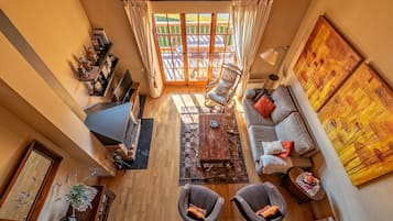 Un salon spacieux avec une grande fenêtre, un canapé, deux fauteuils, une table basse et un téléviseur.